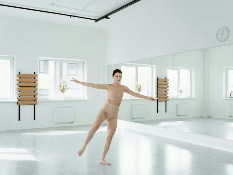 Woman performing a balance pose in a bright studio.